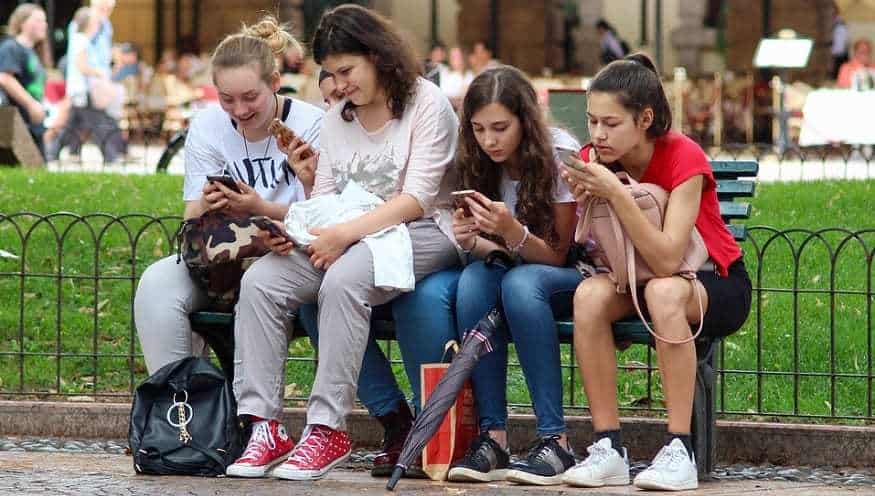 Shopping Party - Teen girls using smartphones on bench