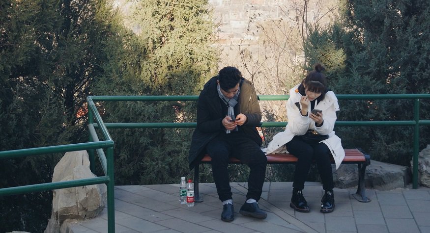 Chinese Social Commerce - man and woman using phones in Beijing
