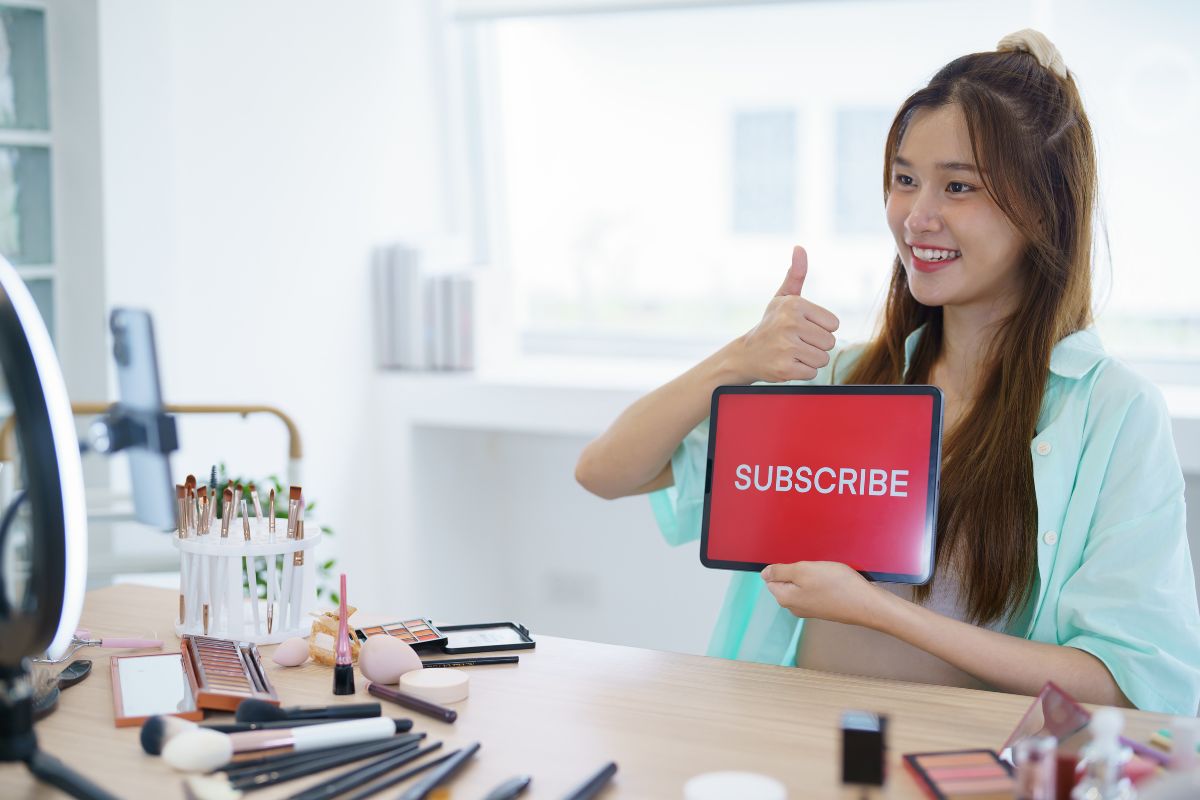Social media influencer - Woman holding up subscribe in front of phone camera