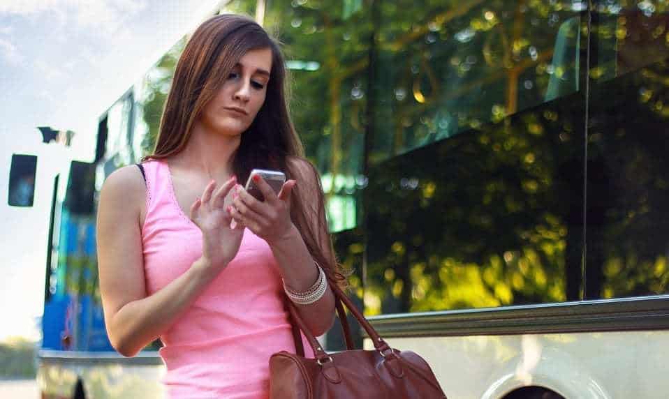 commuter commerce - woman on phone outside of bus