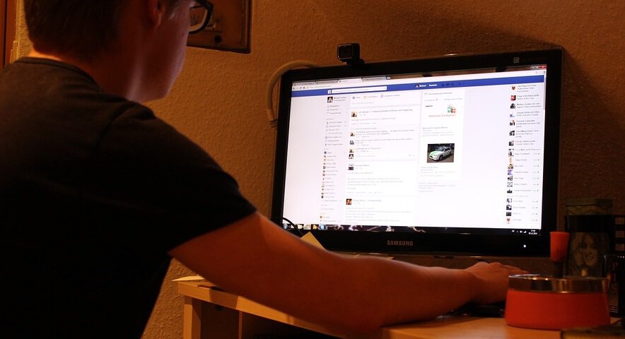 social media account information - person using Facebook on computer