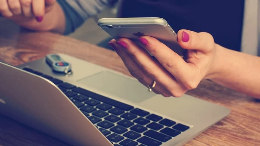 Mobile shopping this holiday season - woman holding phone with laptop